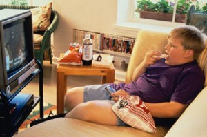 Obese child sitting in front of TV eating junk food